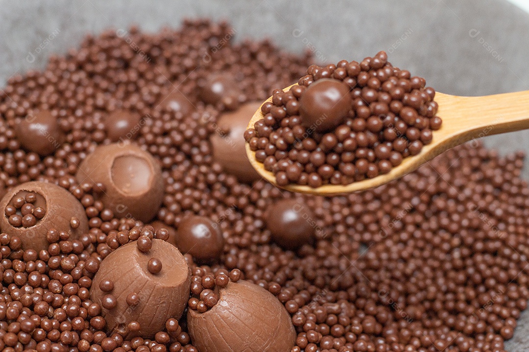 Diferentes tipos de bolas de chocolate em uma tigela cinza com uma colher cheia de chocolate