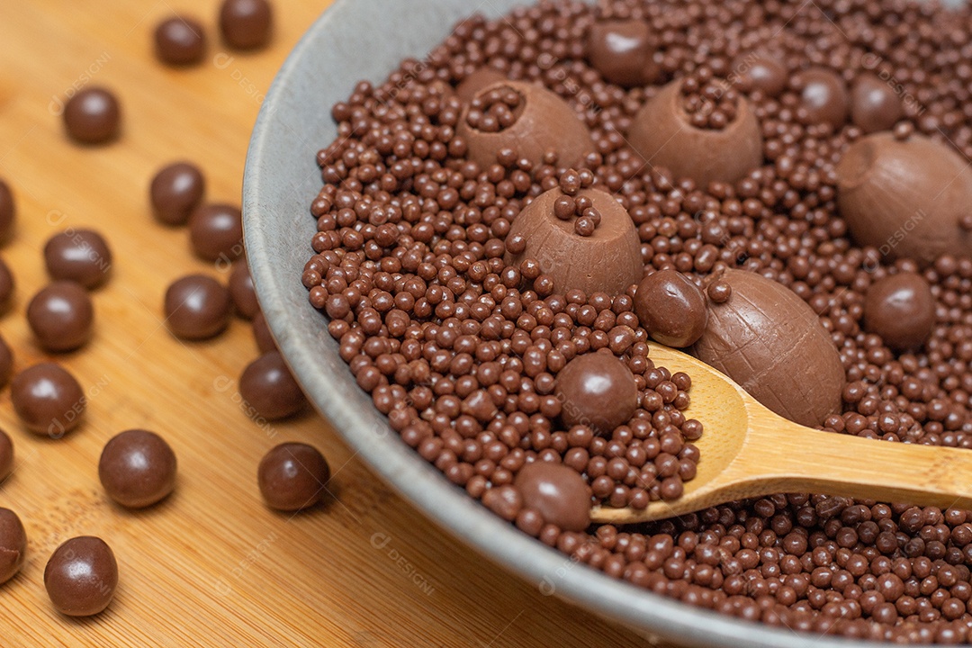 diferentes tipos de bolas de chocolate em uma tigela cinza com uma colher cheia de chocolate