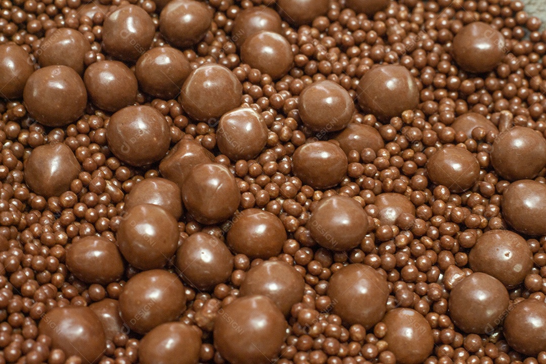 Diferentes tipos de bolas de chocolate em uma tigela cinza com uma colher cheia de chocolate