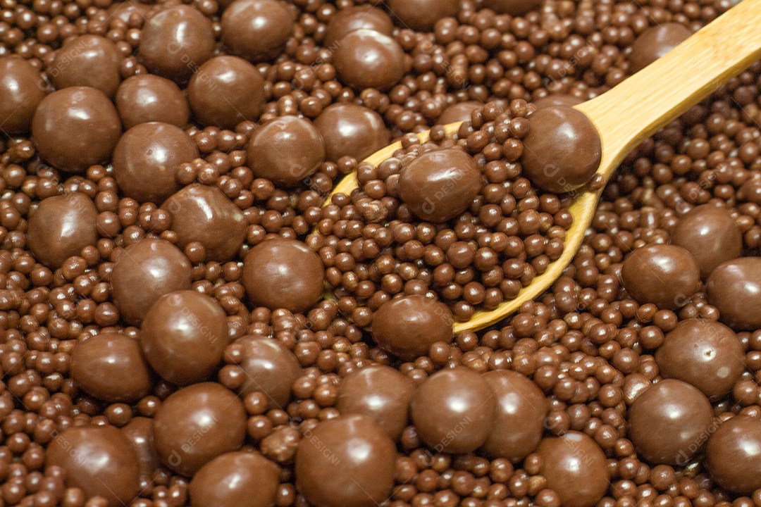 Diferentes tipos de bolas de chocolate em uma tigela cinza com uma colher cheia de chocolate