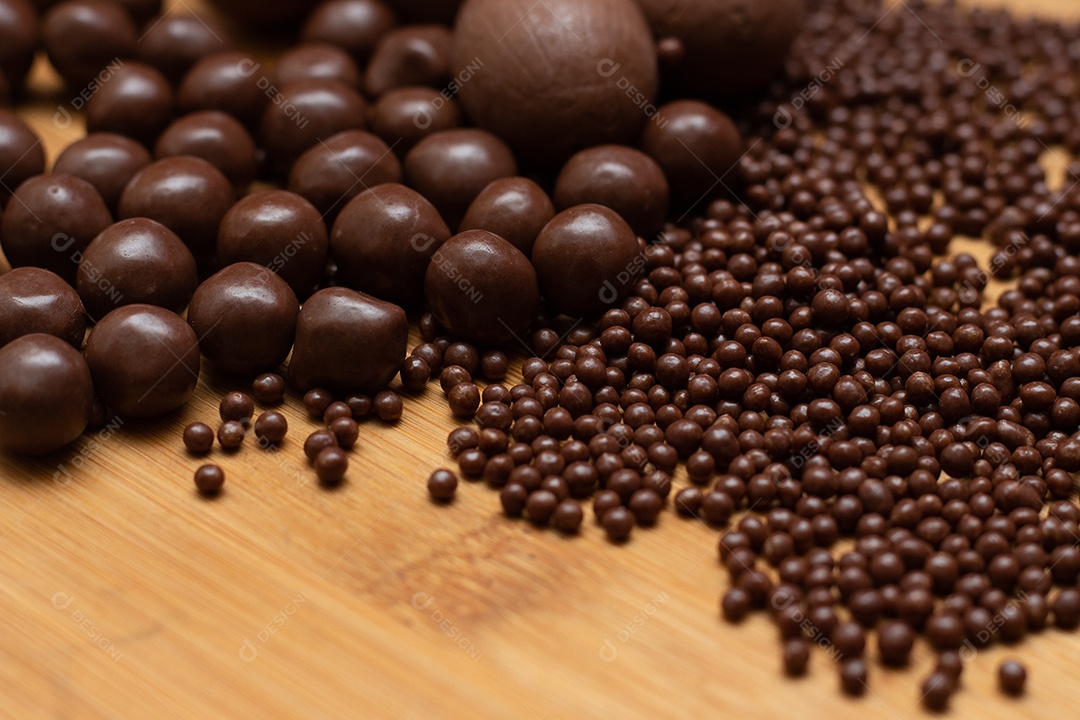 Diferentes tipos de bolas de chocolate em uma tigela cinza com uma colher cheia de chocolate