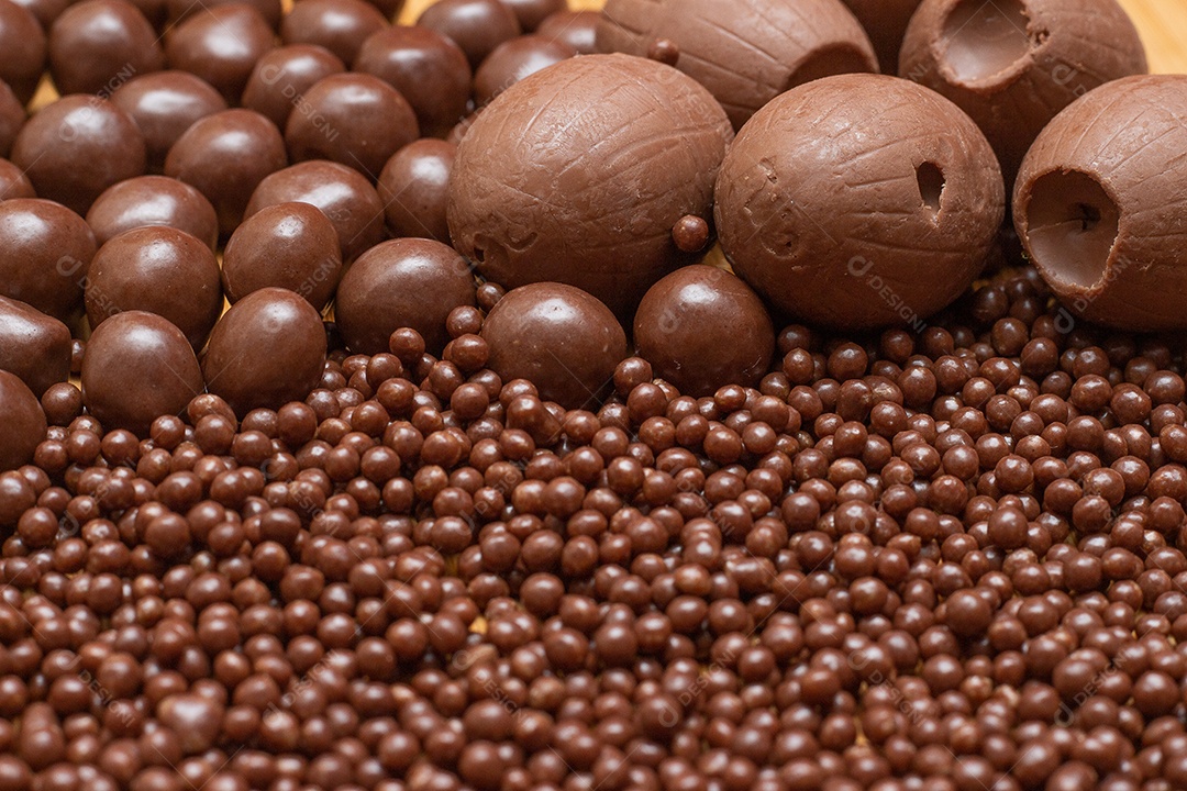 Diferentes tipos de bolas de chocolate em uma tigela cinza com uma colher cheia de chocolate