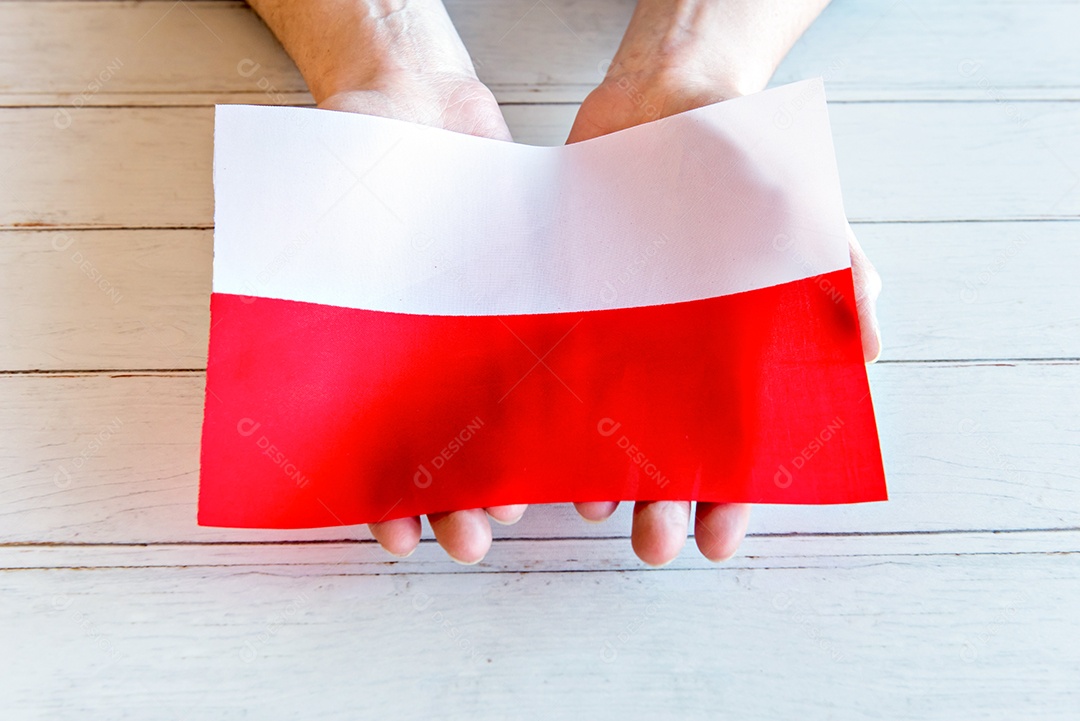 mãos segurando a bandeira polonesa