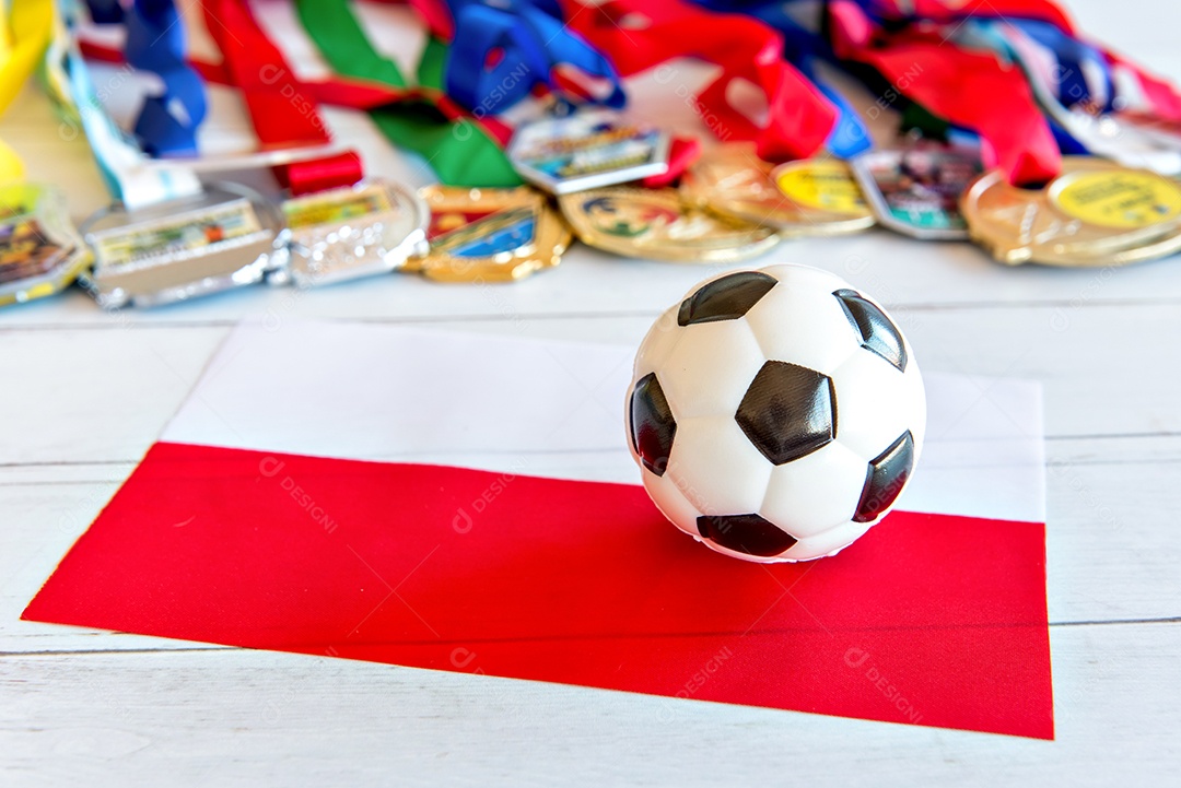 Bola de futebol e bandeira polonesa, medalhas borradas no fundo