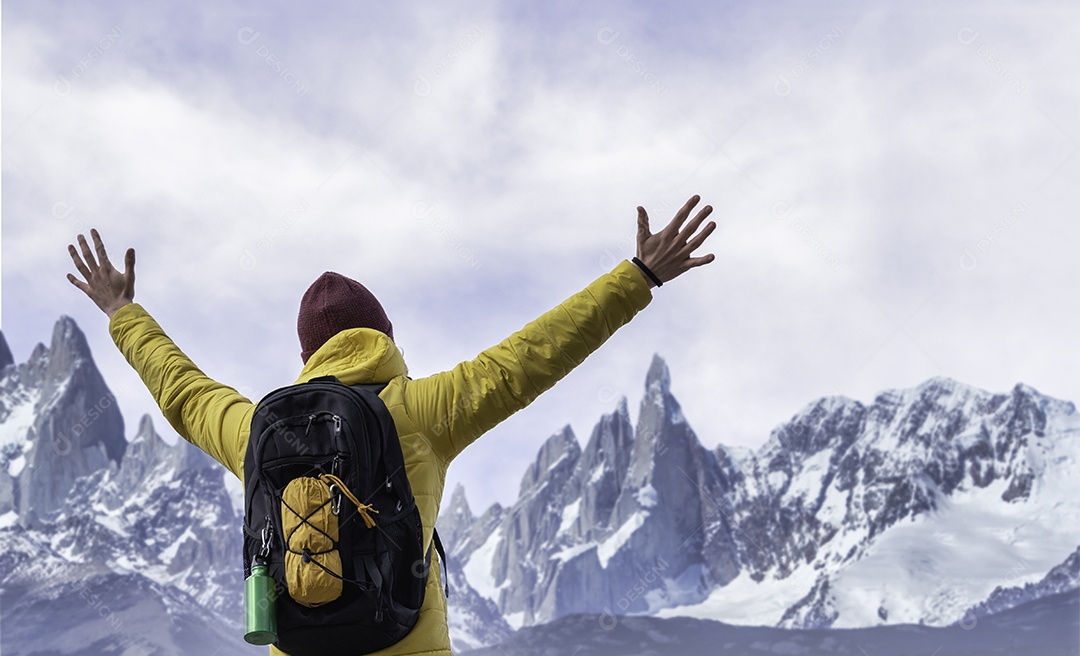 Alpinista com os braços em pé no topo da montanha nevada