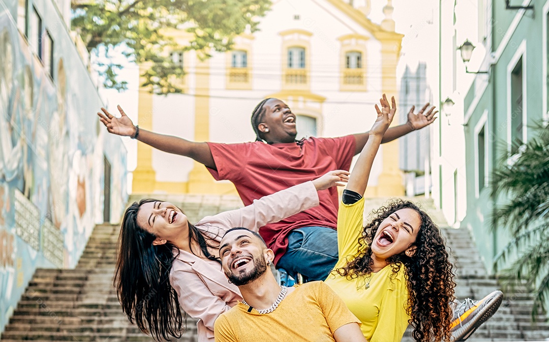 Grupo de jovens amigos multirraciais felizes braços levantados tendo