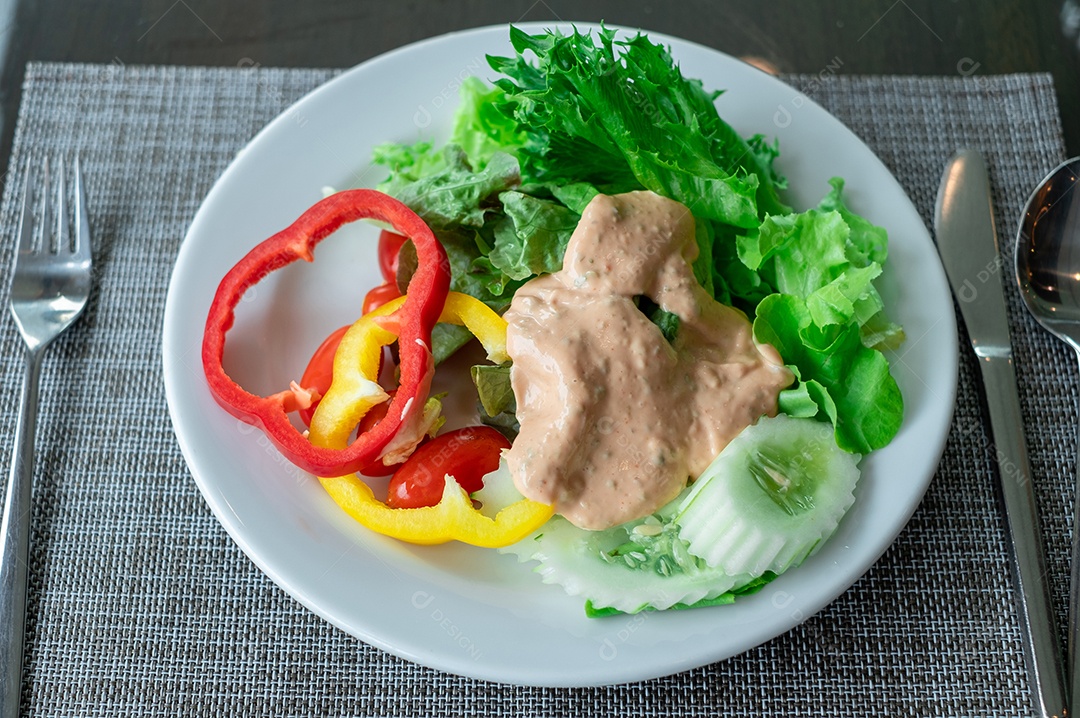 Pimentões vermelhos e amarelos em uma salada de legumes em um prato branco