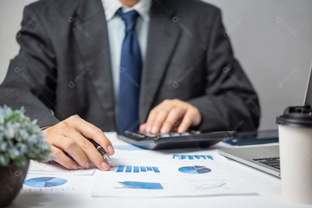 Businessman hand pointing paperwork chart report analysis statistics and document financial graph with laptop computer in office.