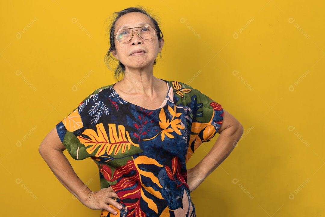 Mulher idosa asiática em pé na cintura em um fundo amarelo.