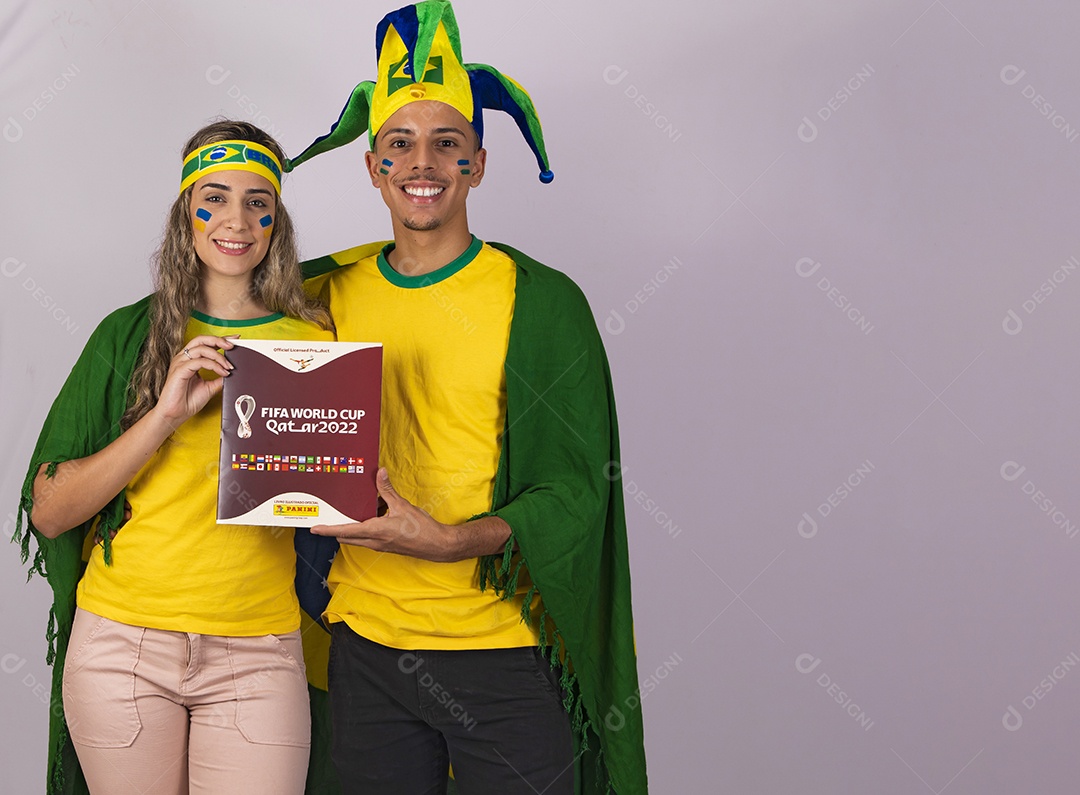 Homem e mulher jovens brasileiros torcedores segurando álbum copa do mundo Futebol