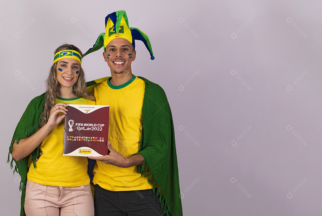 Homem e mulher jovens brasileiros torcedores segurando álbum copa do mundo Futebol