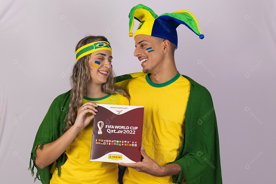 Homem e mulher jovens brasileiros torcedores segurando álbum copa do mundo Futebol
