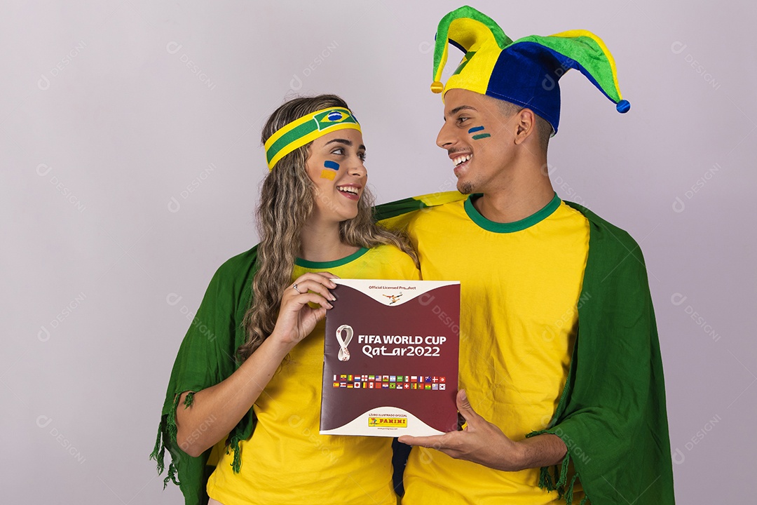 Man and woman young brazilian supporters holding album world cup Football
