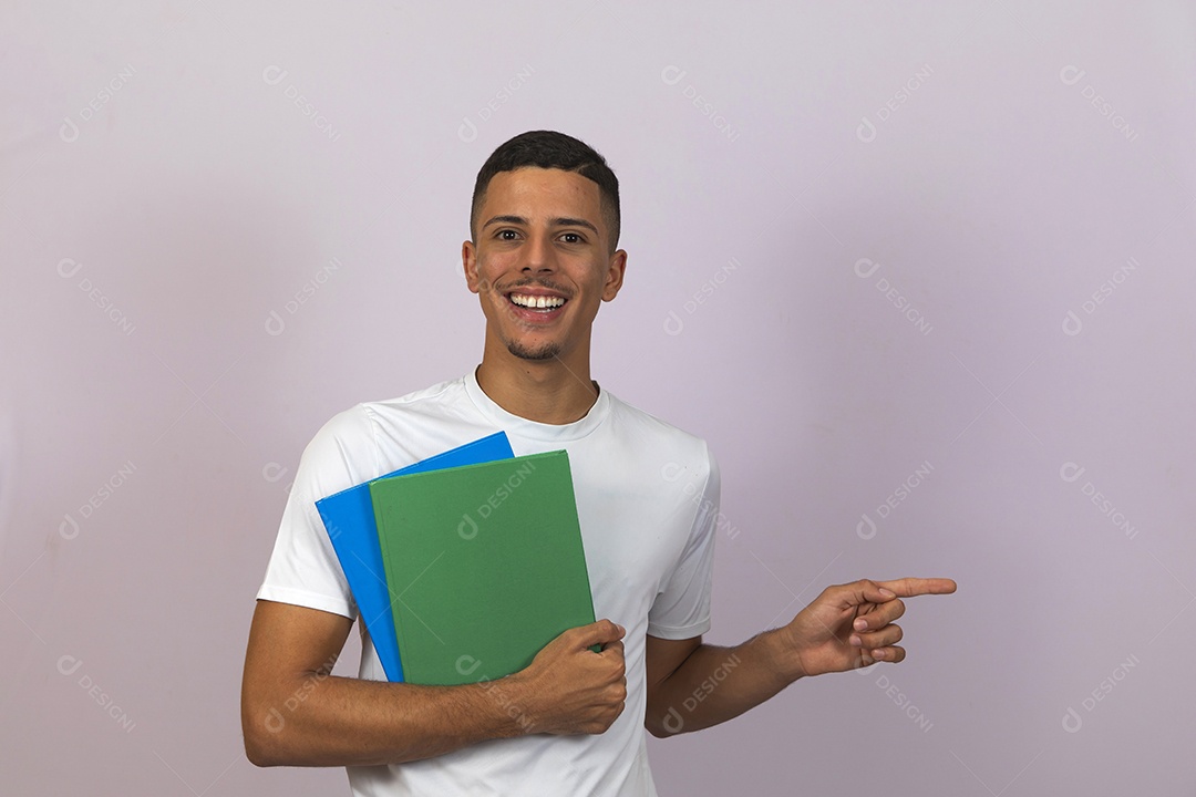 Homem jovem brasileiro estudante segurando materiais escolar sorridente sobre fundo isolado branco