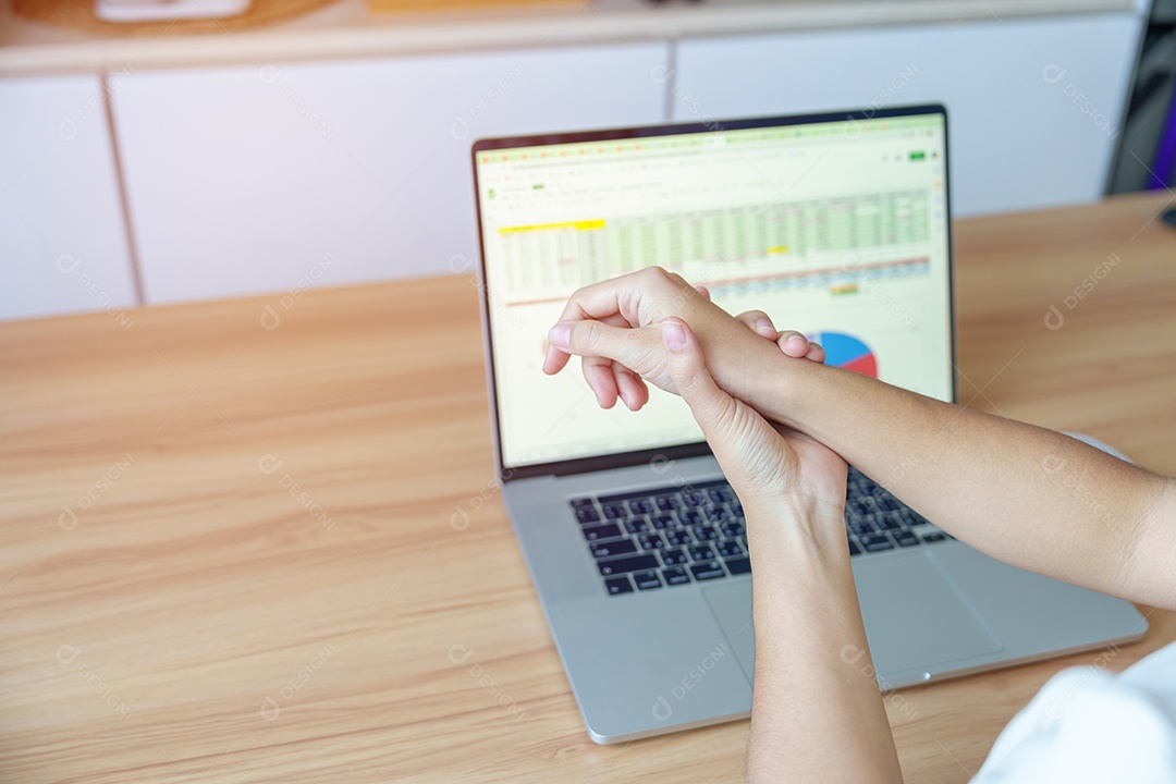 Mulher com dor no pulso ao usar laptop e mouse durante trabalha