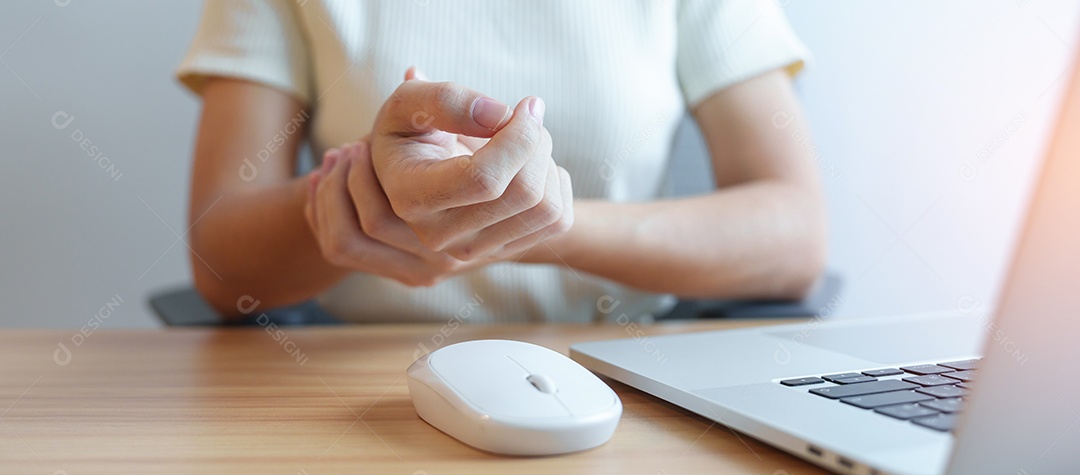 Mulher com dor no pulso ao usar laptop e mouse durante trabalha