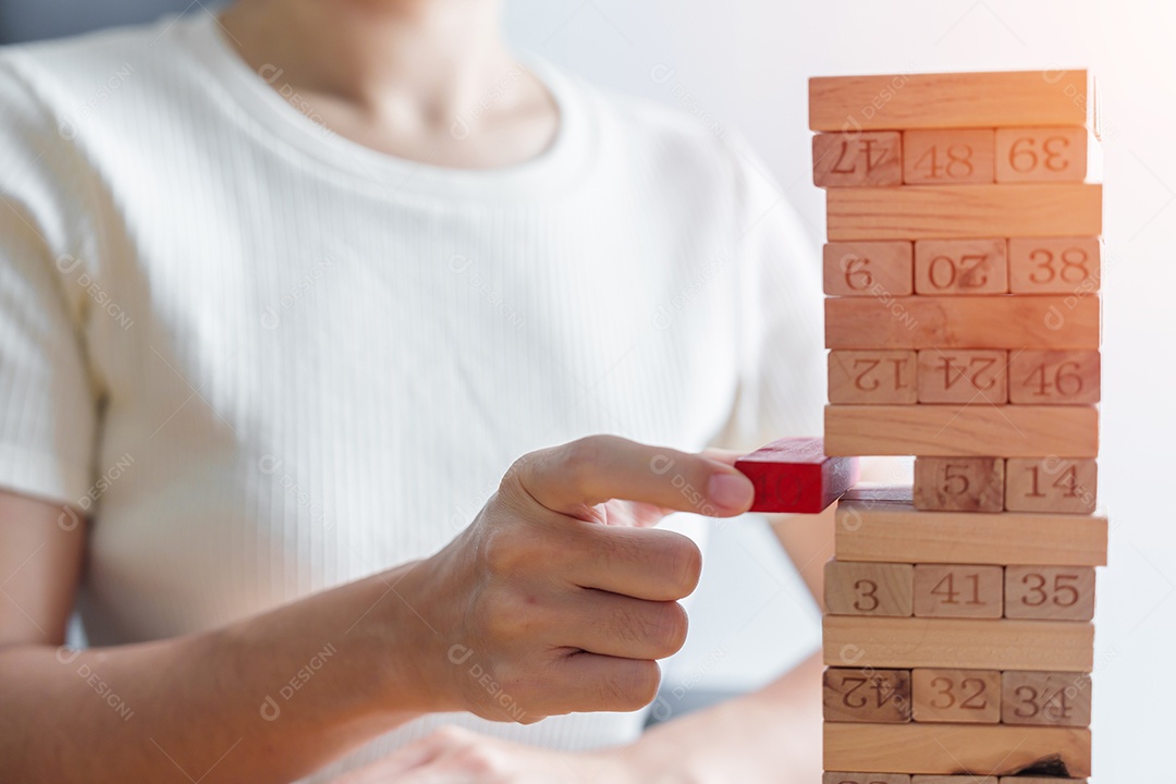 Mão colocando ou puxando bloco de madeira na torre. Plano de negócios