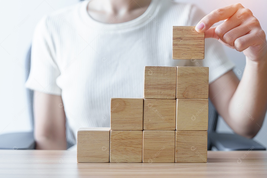 Mão de mulher colocando bloco de madeira no prédio. Liderança, Negócios