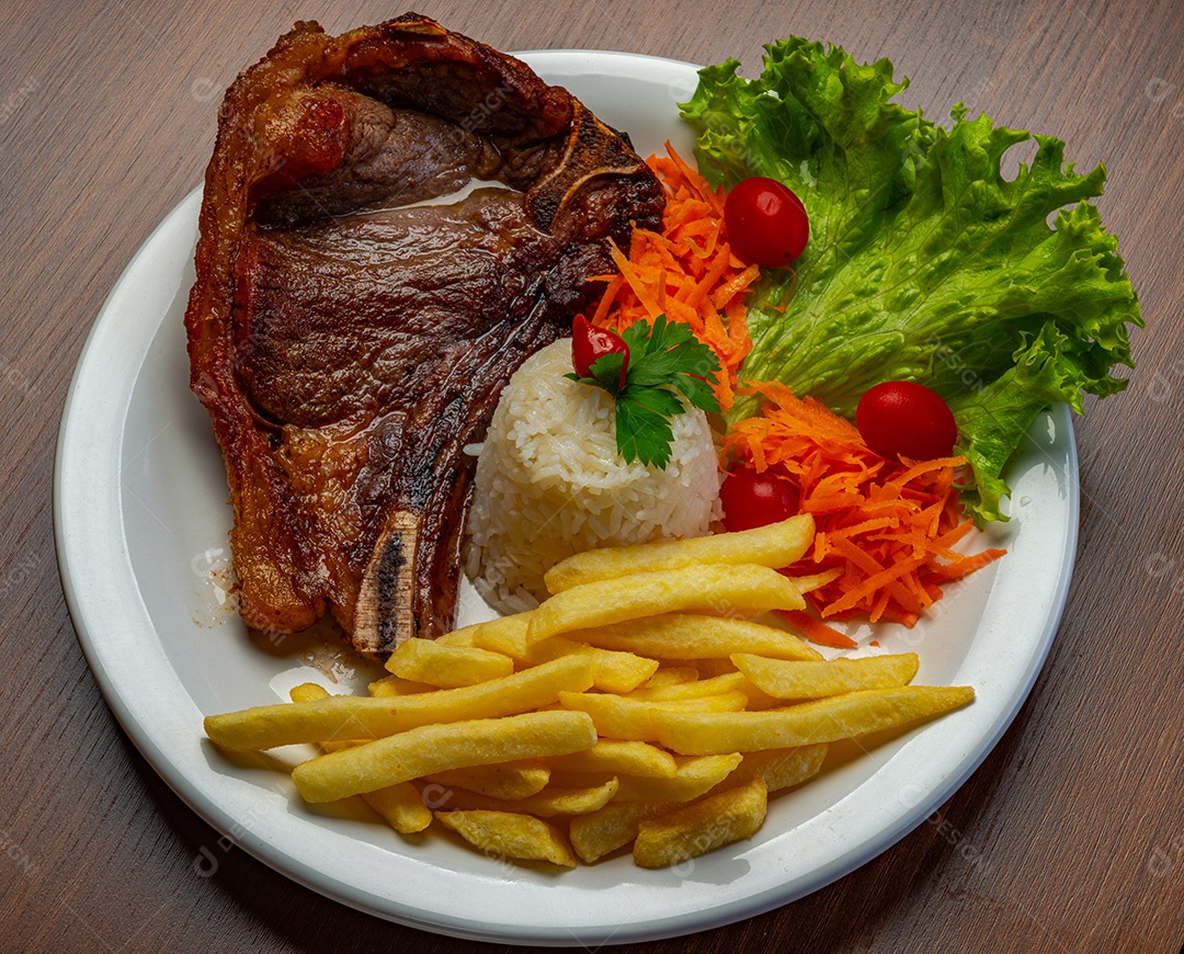 Filé com fritas, servido com arroz e salada de alface, tomate e cenoura.