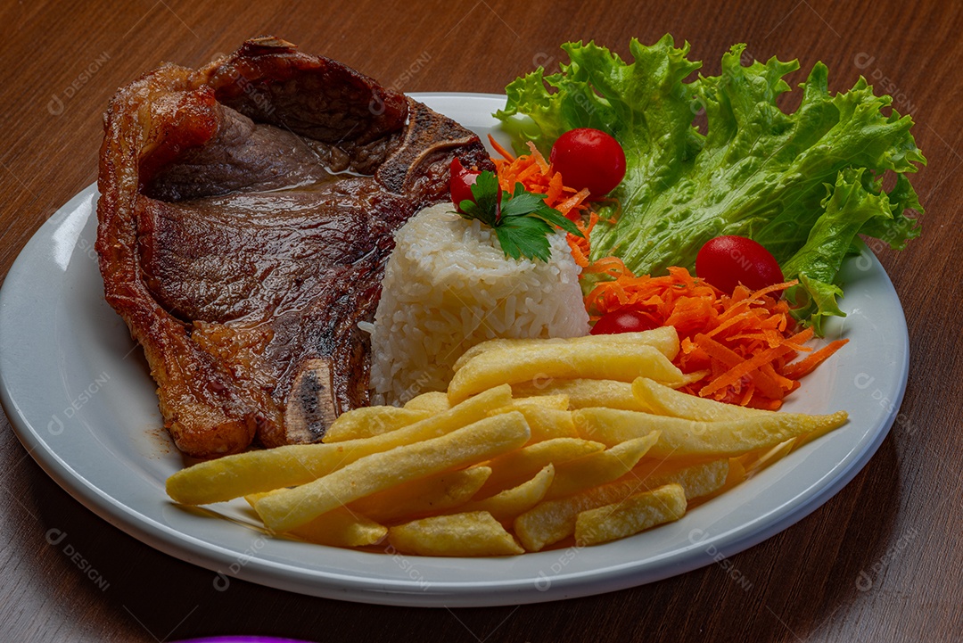 Filé com fritas, servido com arroz e salada de alface, tomate e cenoura.