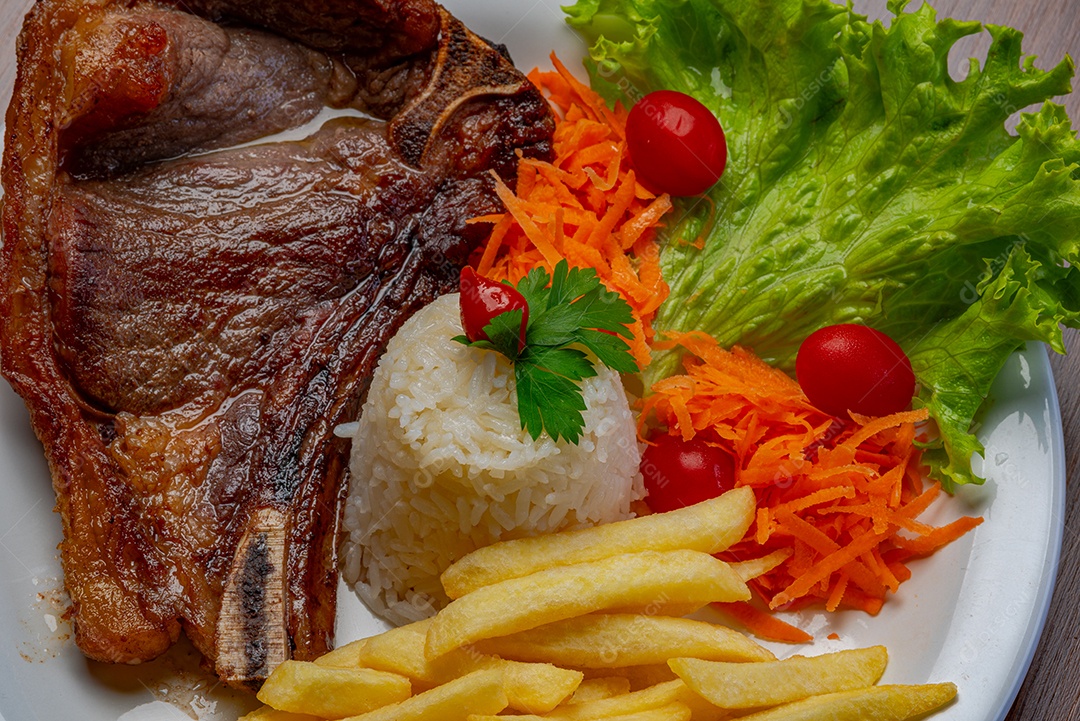 Filé com fritas, servido com arroz e salada de alface, tomate e cenoura.