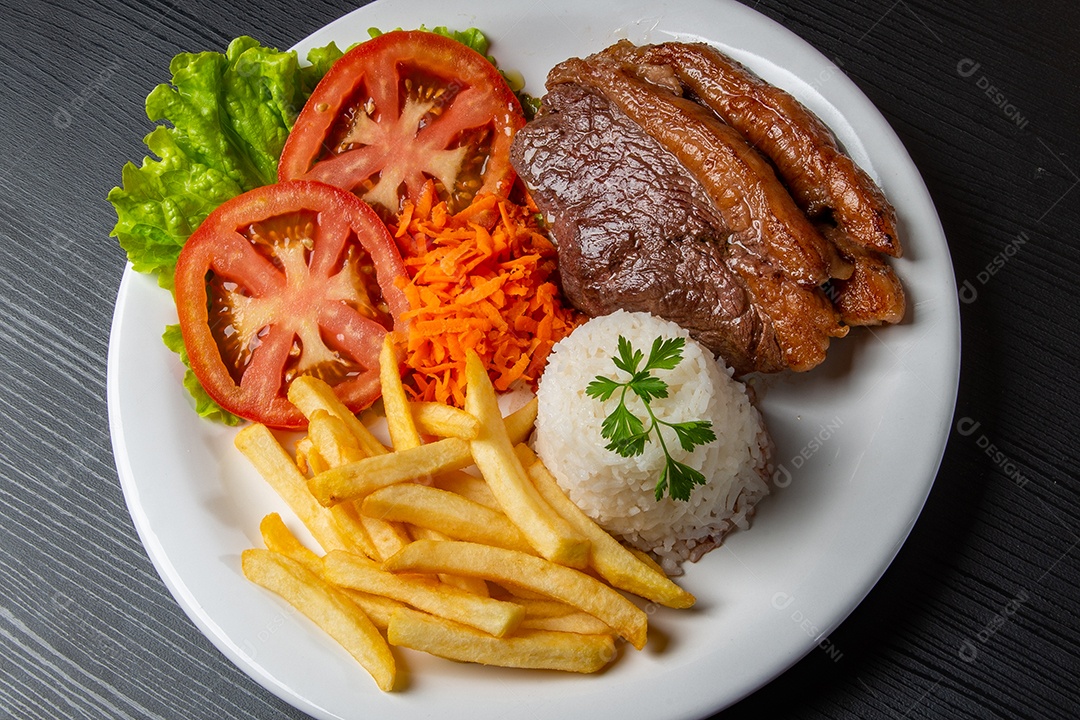 Fried steak served with rice and lettuce, tomato and carrot salad.