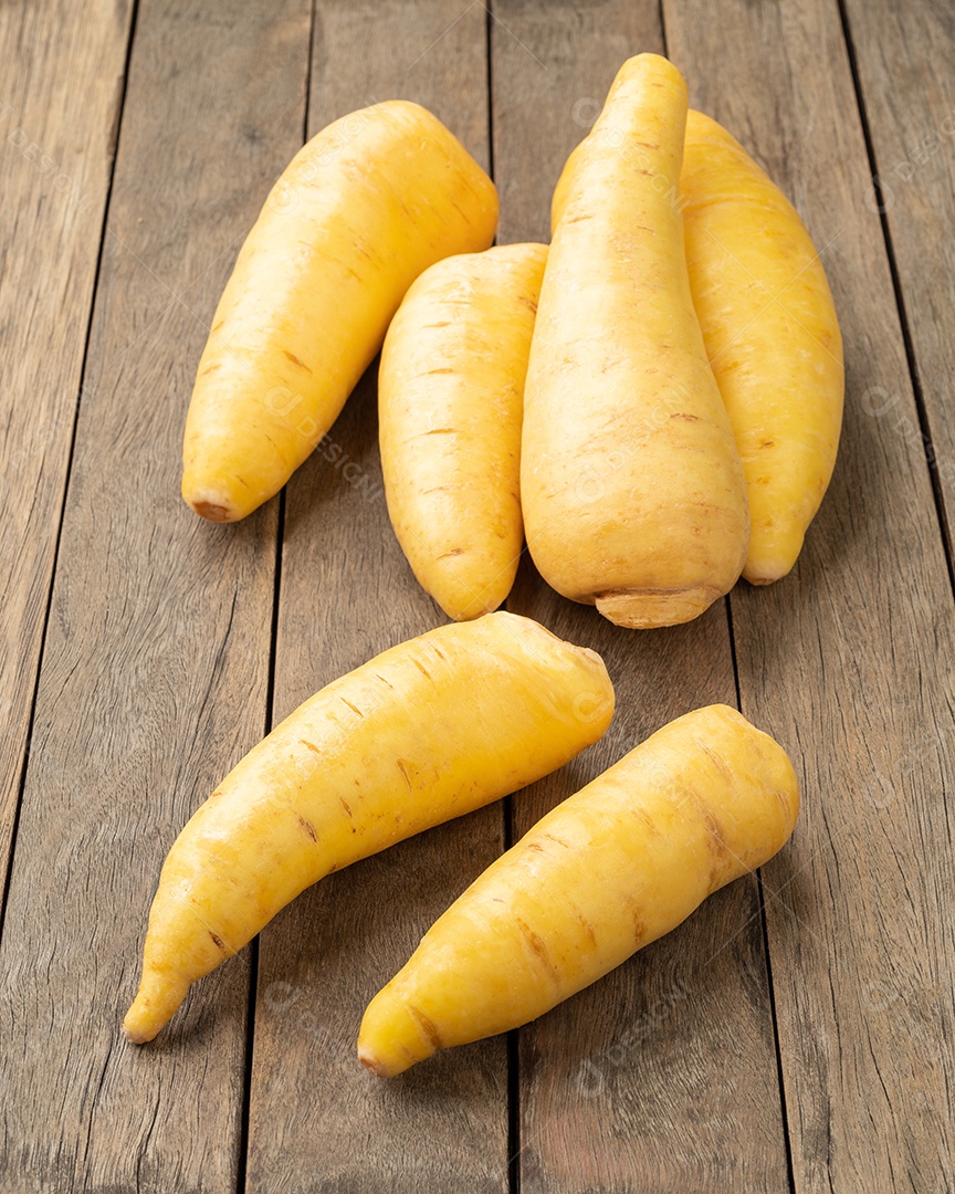 Mandioquinha crua sobre mesa de madeira.