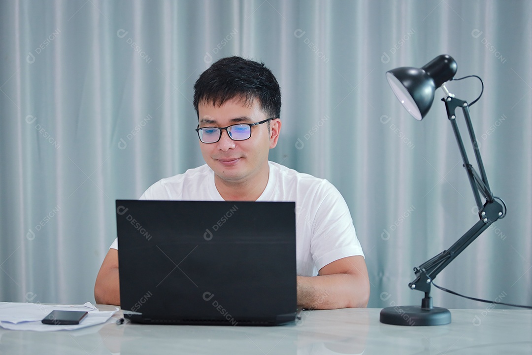 tecnologia, trabalho remoto e conceito de estilo de vida - homem asiático feliz em óculos com computador portátil trabalhando em home office ou compras on-line, trabalho em casa, freelance, aprendizado on-line, estudando.