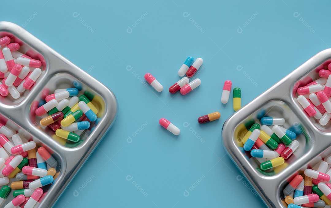 Pílula de cápsula antibiótica multicolorida na bandeja e fundo azul