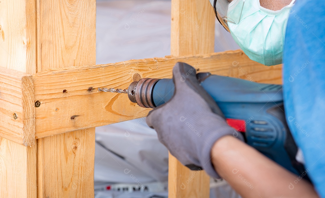 Técnico perfurando caixa de madeira com furadeira. máquina pesada
