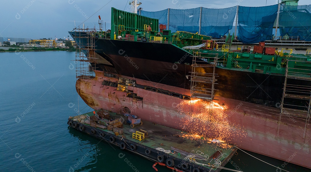 Navio porta-contentores de carga no serviço de manutenção do conceito de doca seca trabalhando no mar. Conceito de navio de carga de seguro e manutenção. corte de metal de navio com gás
