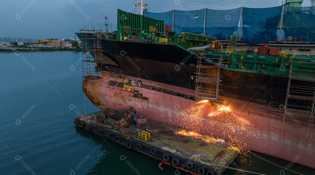 Navio porta-contentores de carga no serviço de manutenção do conceito de doca seca trabalhando no mar. Conceito de navio de carga de seguro e manutenção. corte de metal de navio com gás