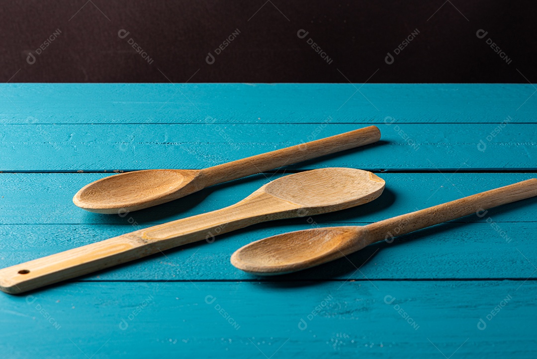 Colheres de pau em uma mesa de madeira rústica azul.