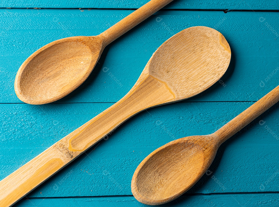 Colheres de pau em uma mesa de madeira rústica azul.