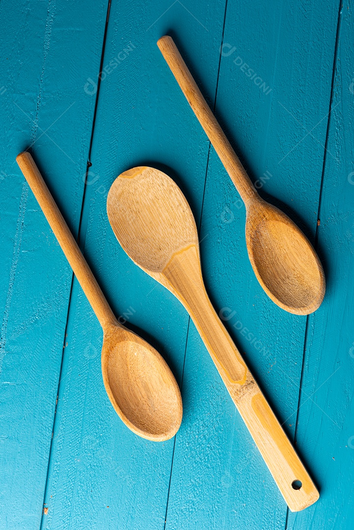 Colheres de pau em uma mesa de madeira rústica azul.
