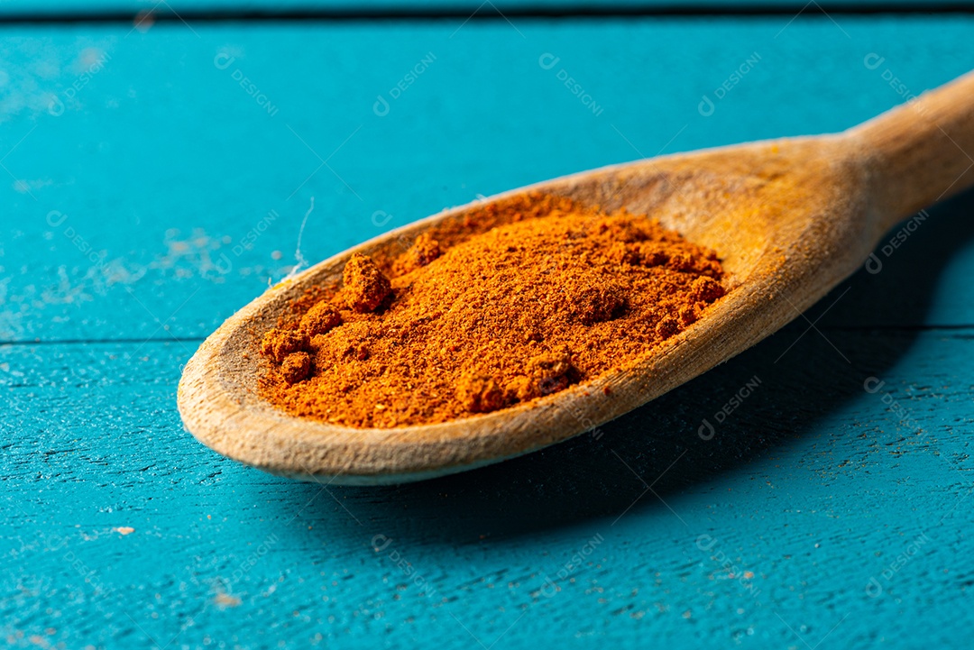 Colheres de pau com especiarias em uma mesa de madeira rústica azul.