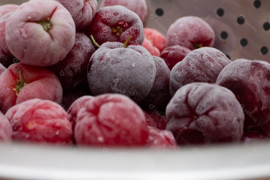 Tigela cheia de acerolas congeladas e frescas