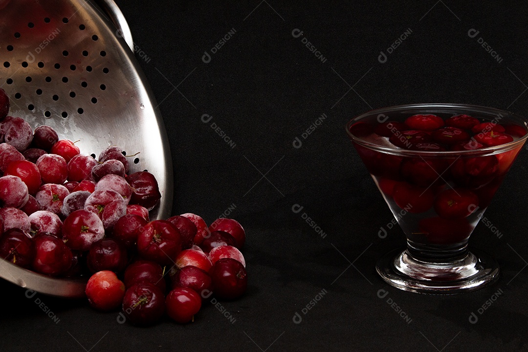 Tigela cheia de acerolas frescas ao lado de suco de acerola