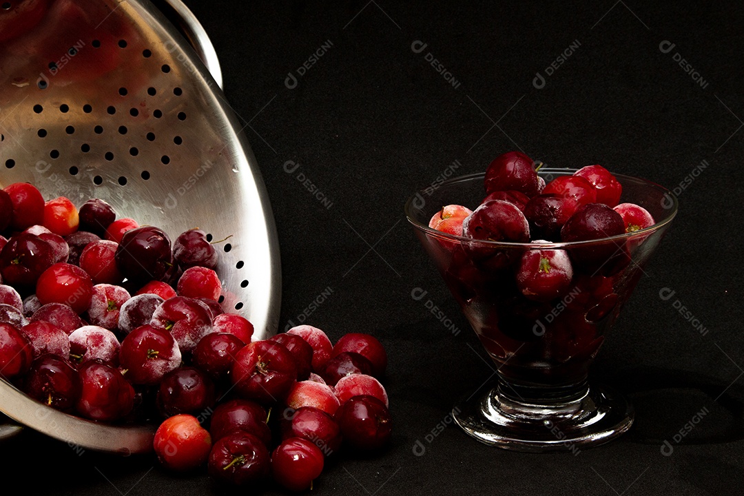 Tigela cheia de acerolas frescas ao lado de suco de acerola