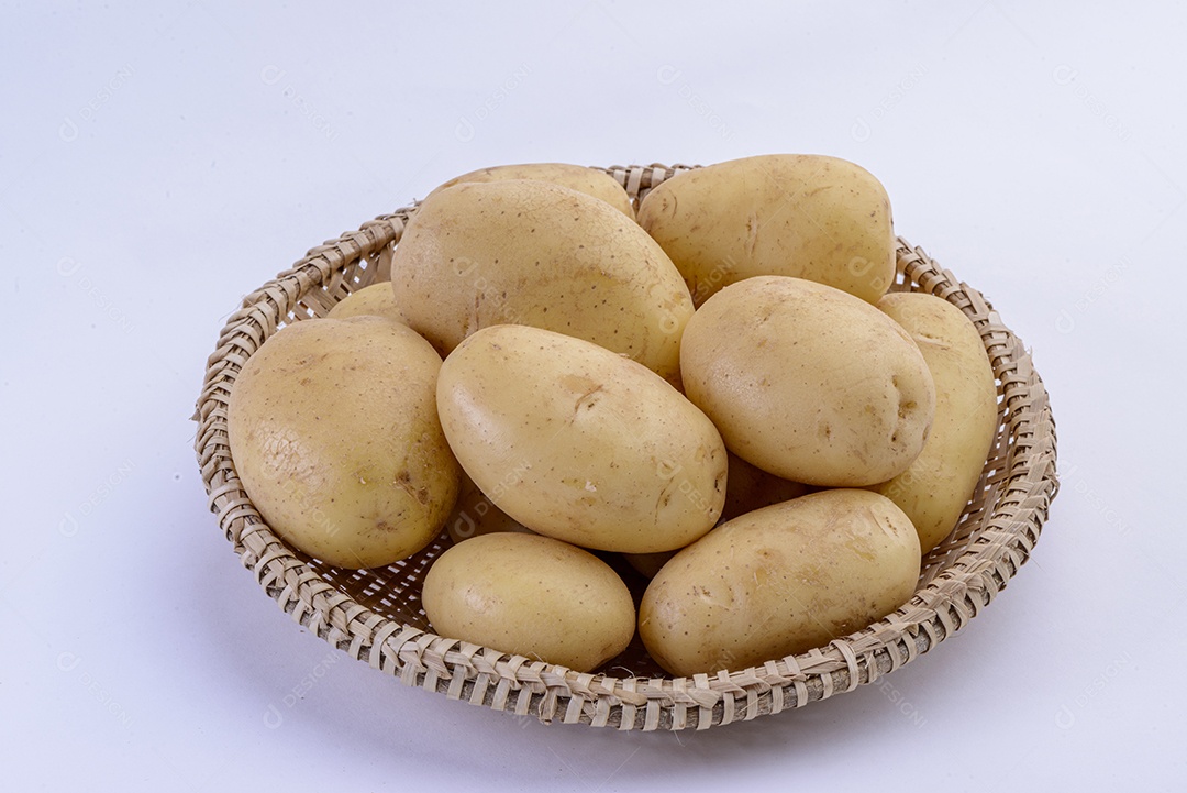 Batatas dentro da cesta de palha isolada no fundo branco.