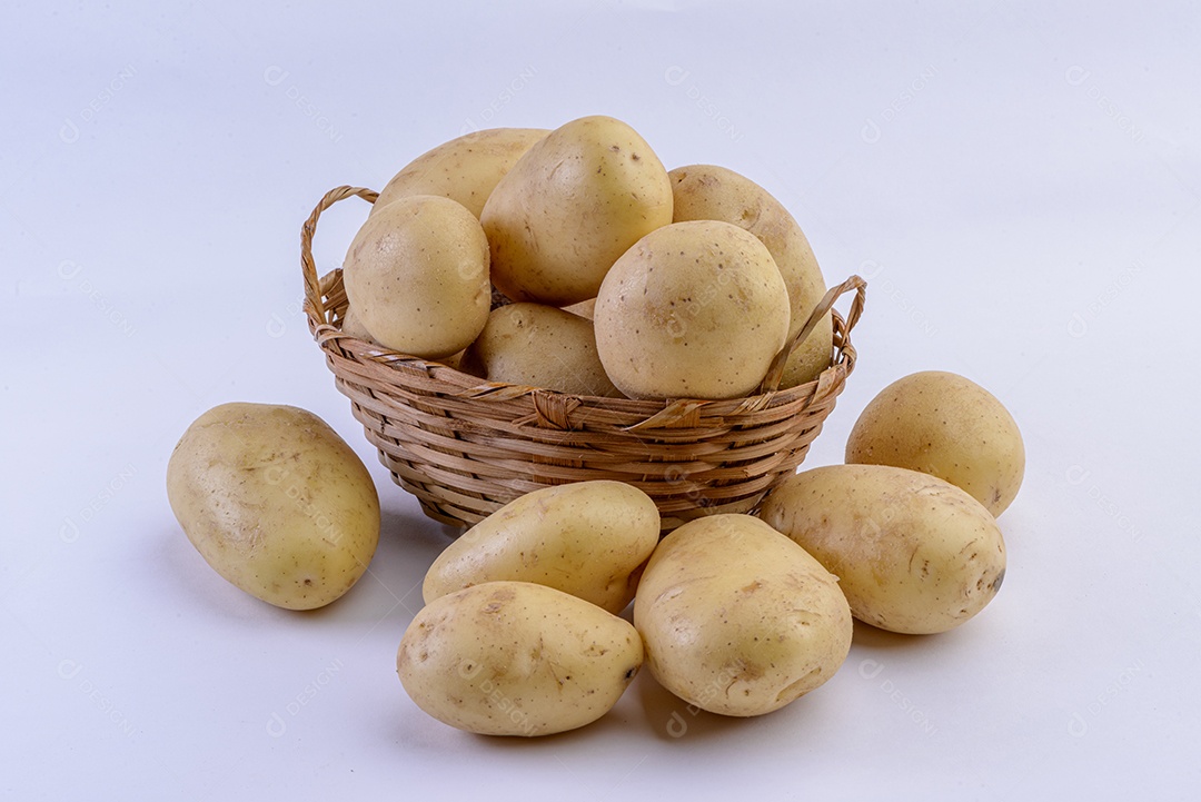 Batatas dentro da cesta de palha isolada no fundo branco.