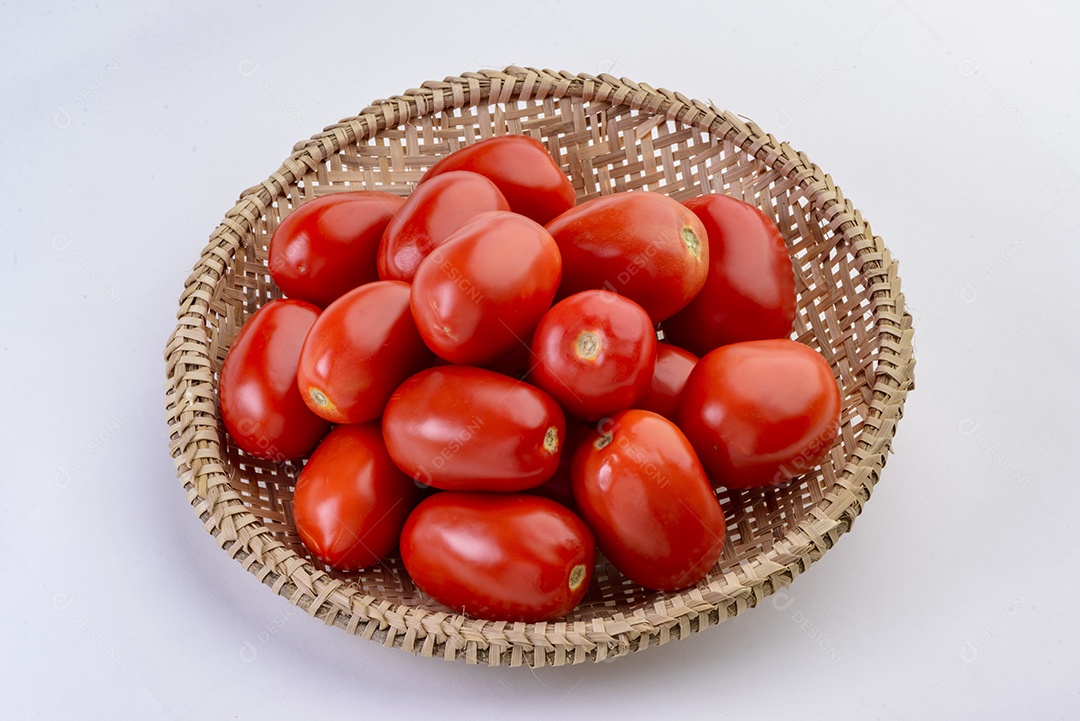 Tomates dentro da cesta de palha isolada no fundo branco.