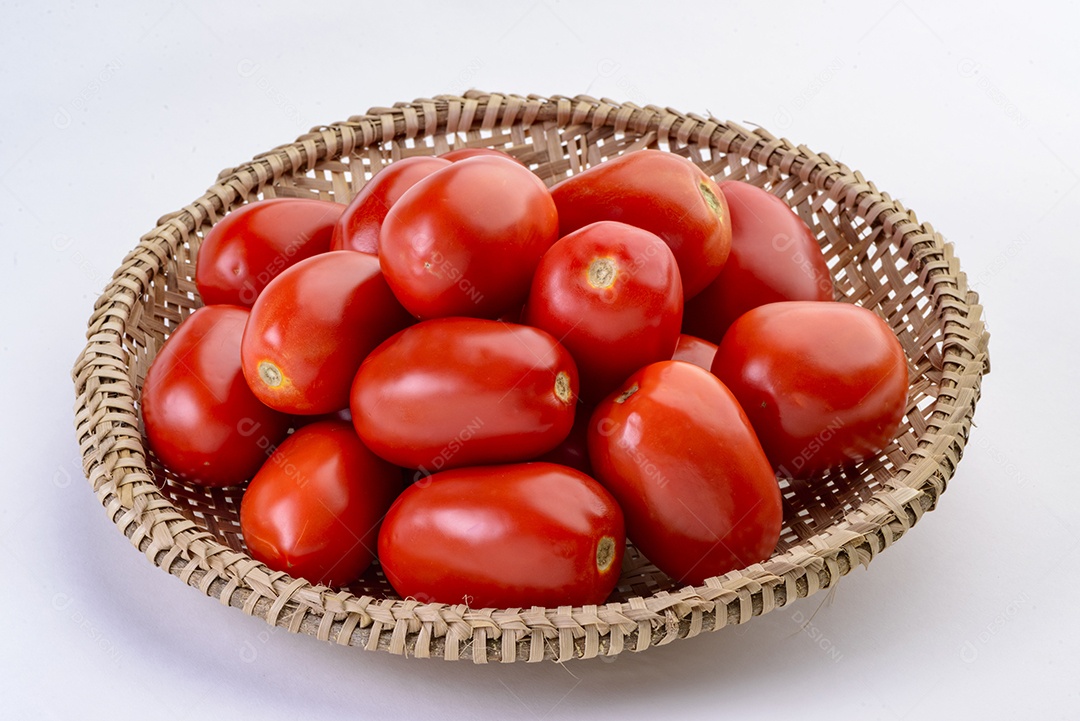 Tomates dentro da cesta de palha isolada no fundo branco.