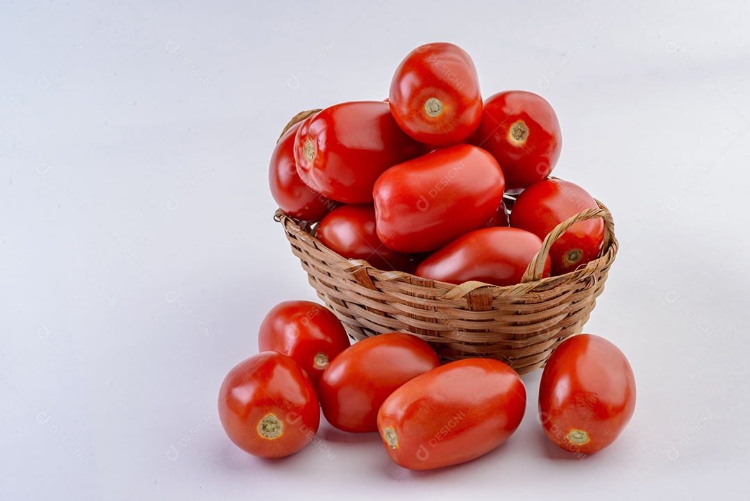 Tomates dentro da cesta de palha isolada no fundo branco.