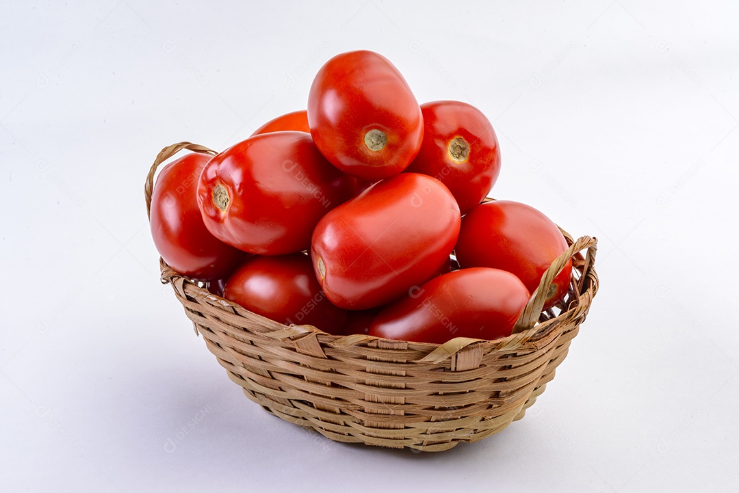 Tomates dentro da cesta de palha isolada no fundo branco.