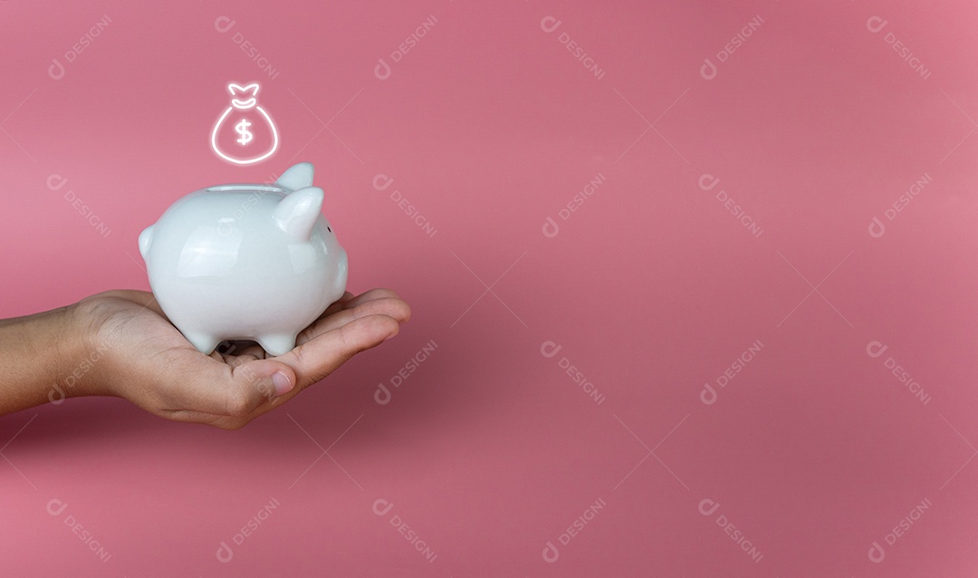 Mão segurando um cofrinho branco sobre um fundo rosa. Economizando.