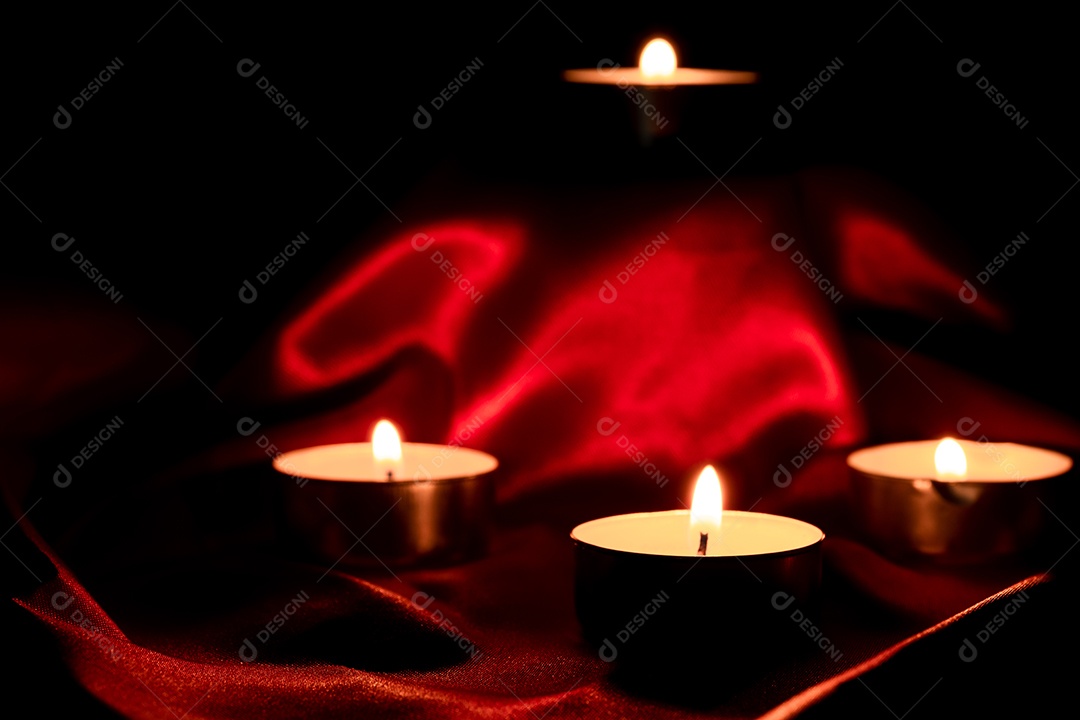 Luz de vela e fundo de tecido vermelho na escuridão