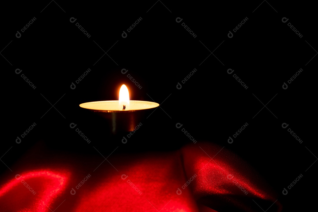 Luz de vela e fundo de tecido vermelho na escuridão