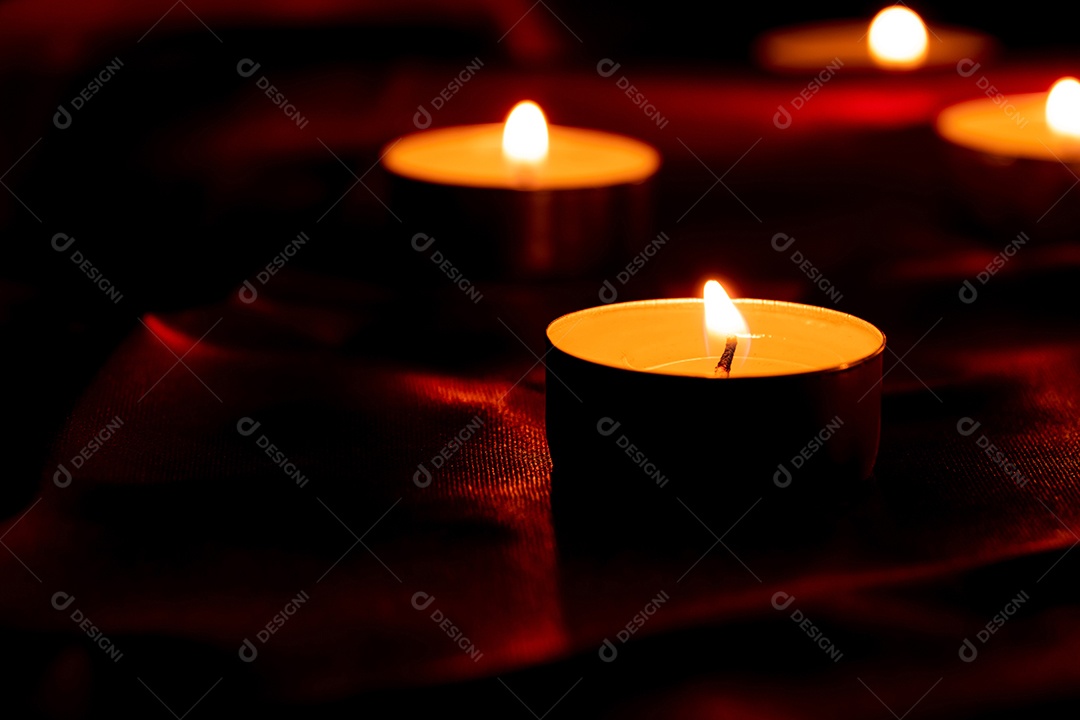 Luz de vela e fundo de tecido vermelho na escuridão