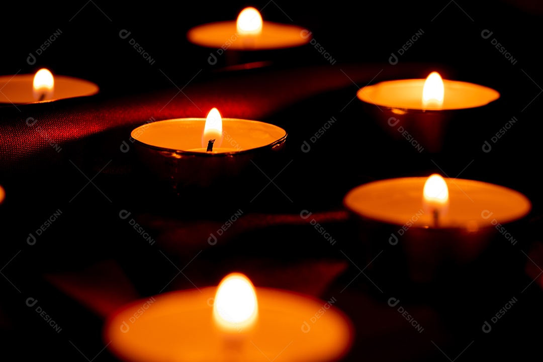 Luz de vela e fundo de tecido vermelho na escuridão